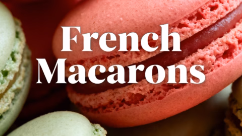 ingredients image of a flat lay photo from above of the ingredients for French Macarons including almond flour powdered sugar egg whites granulated sugar and food coloring arranged aesthetically on a light colored surface with natural light