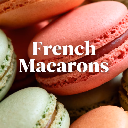 ingredients image of a flat lay photo from above of the ingredients for French Macarons including almond flour powdered sugar egg whites granulated sugar and food coloring arranged aesthetically on a light colored surface with natural light