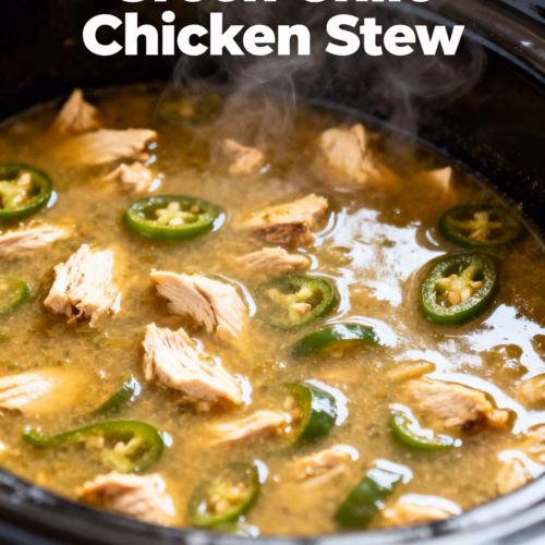 image of a beautifully arranged flat lay of fresh ingredients for crockpot green chile chicken stew including chicken breasts green chiles onions garlic chicken broth and spices on a rustic wooden background with natural lighting