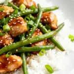 image of chicken breasts cut into cubes fresh green beans honey low sodium soy sauce garlic cloves olive oil chicken broth grated ginger arrowroot powder green onions sesame seeds red pepper flakes neatly arranged in healthy clear glass bowls and rustic brown wooden kitchen sets top down on a white marble kitchen counter under soft diffuse daylight realistic