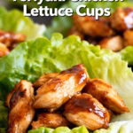 image of fresh chicken breast butter lettuce leaves garlic ginger green onions bell peppers carrots soy sauce coconut aminos brown sugar sesame seeds arranged on white marble counter with clear glass bowls and rustic brown wooden cutting boards under soft daylight